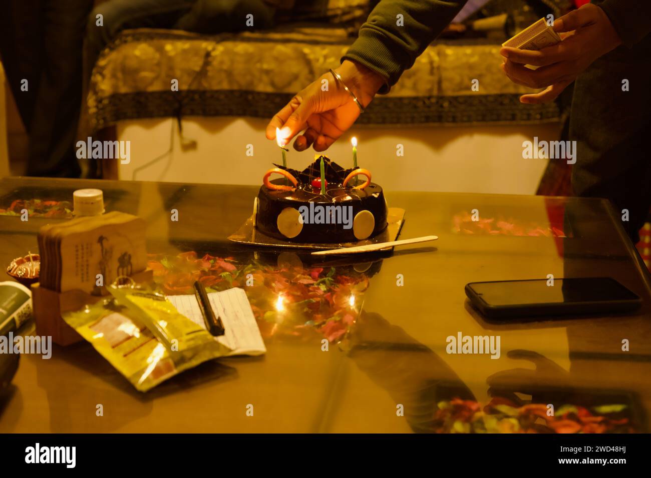 Uomo che accende le candele sulla torta di compleanno con decorazioni al cioccolato Foto Stock