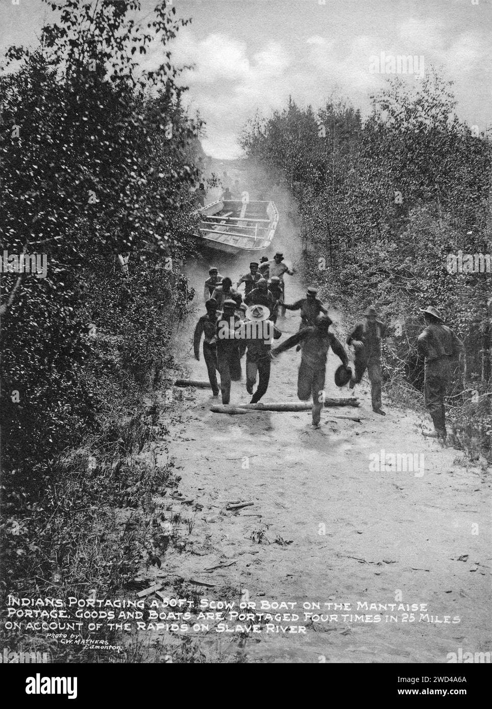 Una fotografia del 1901 di un cargo a fondo piatto trasportato via terra (in modo leggermente incontrollato) presso il Mantaise Portage sul fiume Slave in Alberta/territori del Nord-Ovest, scattata da C W Mathers in una spedizione nell'estremo nord del Canada e pubblicata nel suo libro "il Nord lontano". Mathers ha didascalato questa fotografia: Gli indiani [popolo delle prime Nazioni] hanno portato un'altezza di 50 metri. Naviga o naviga sul Mackenzie Portage. Merci e barche vengono trasportate quattro volte in 25 miglia a causa delle rapide sul fiume Slave. Foto Stock