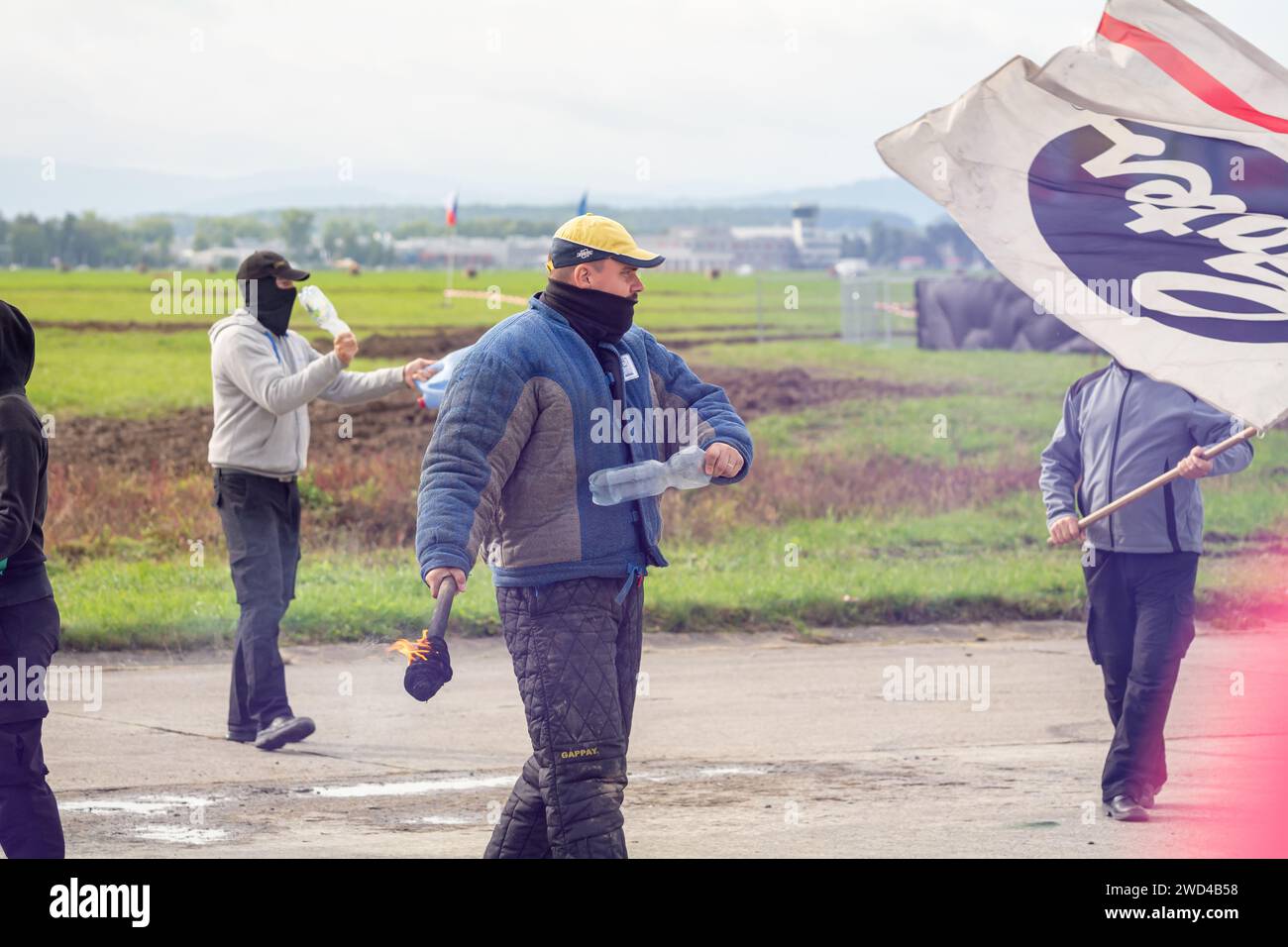 Rivoltosi e manifestanti alla manifestazione di disordini civili durante lo spettacolo aereo NATO Days. Persone arrabbiate con bandiere, bottiglie, oggetti e fuoco. Foto Stock