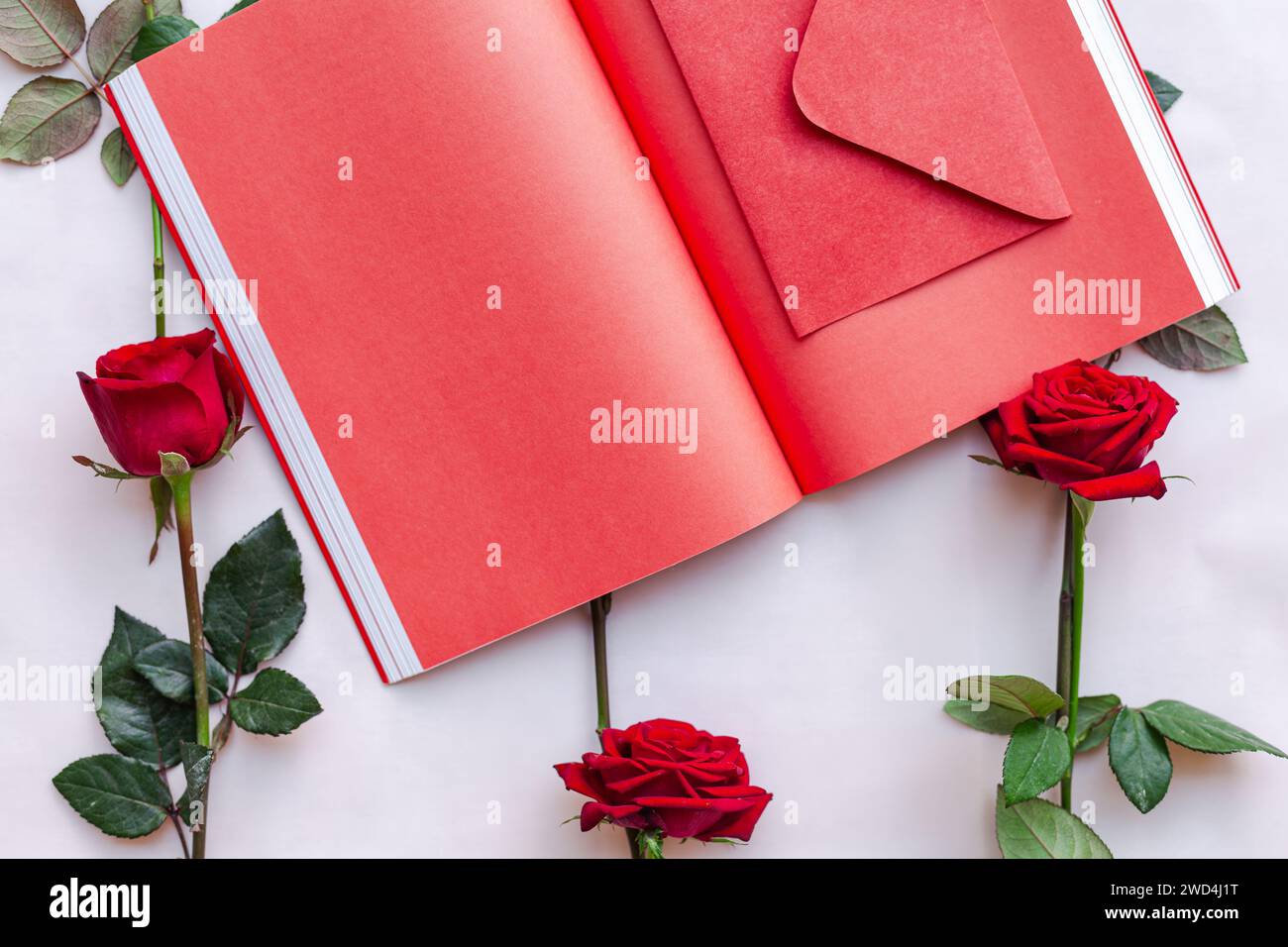 Libro aperto sul tavolo con tre rose rosse Foto Stock