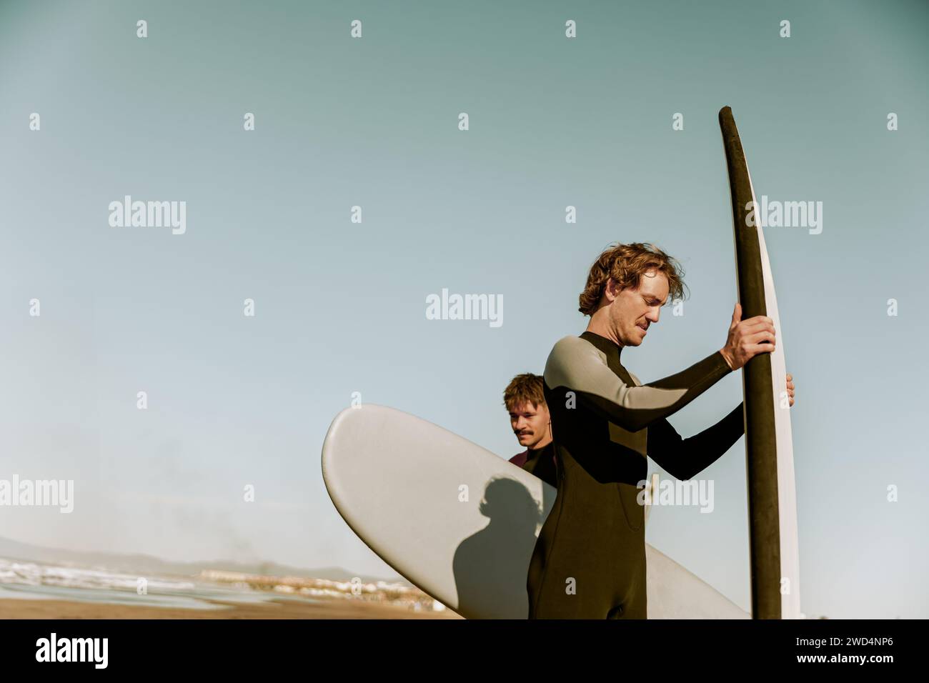 Gruppo di amici surfisti in muta con tavole da surf e si preparano a cavalcare sulle onde Foto Stock