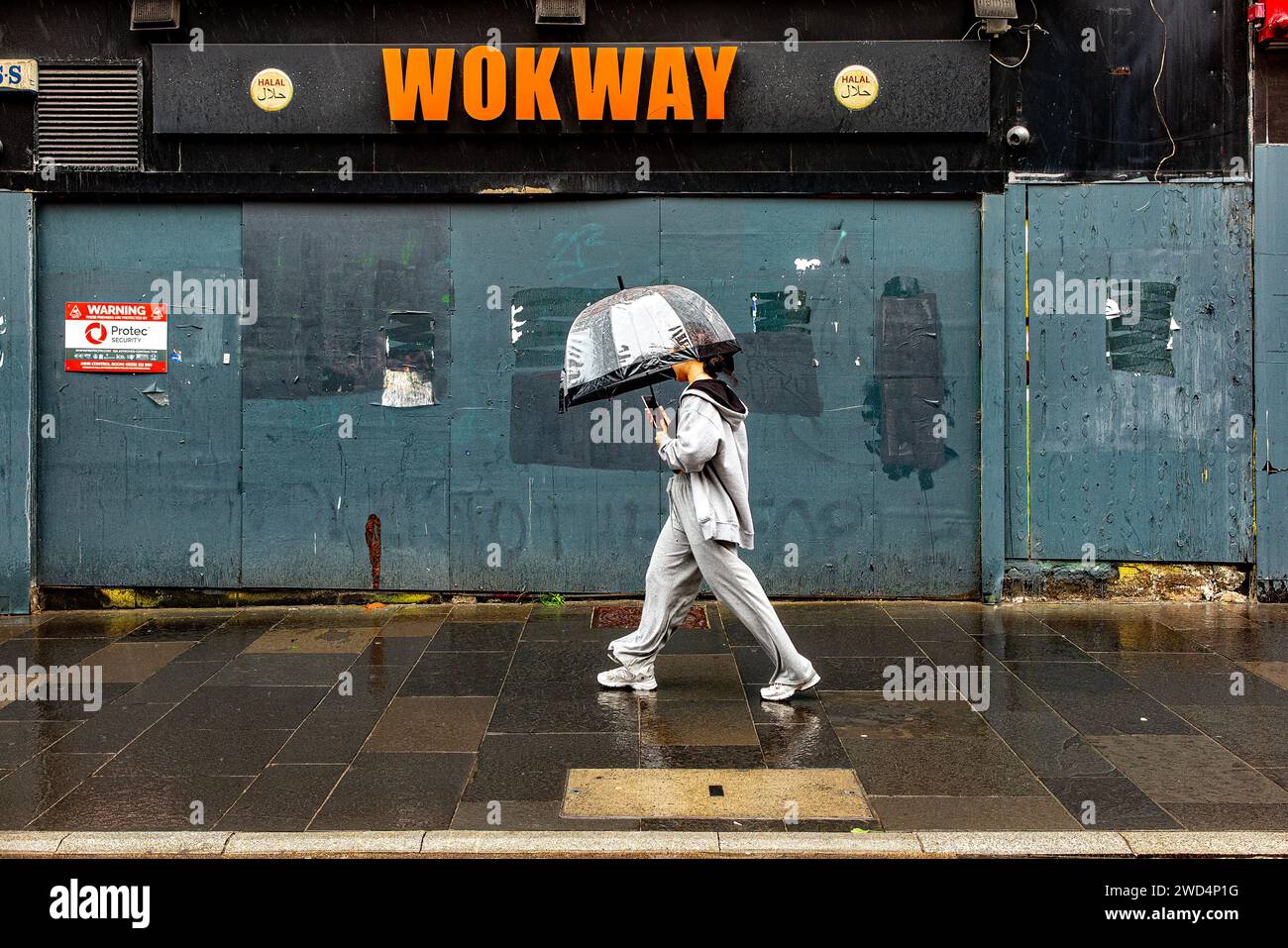 Una ragazza con ombrellone passeggia davanti al ristorante abbandonato sotto la pioggia estiva. Foto Stock