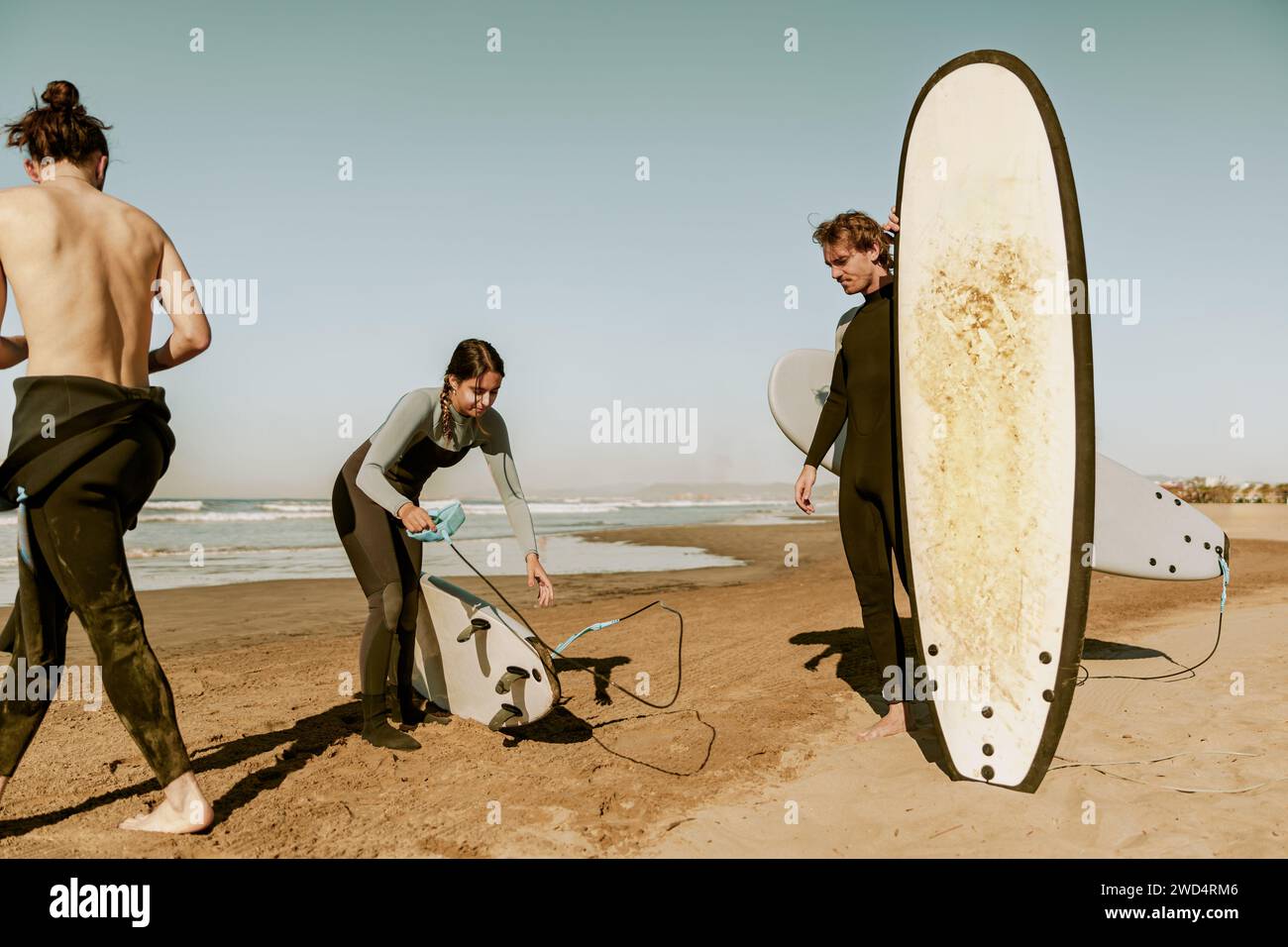 Fai surf in muta sulla spiaggia con le tavole da surf e preparati a cavalcare le onde Foto Stock