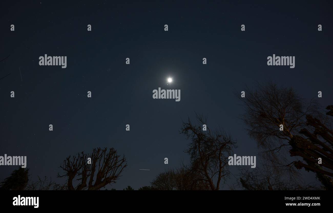 Londra, Regno Unito. 18 gennaio 2024. Giove e la Luna della Terra (al centro) hanno un incontro ravvicinato nel cielo ghiacciato sopra Epsom con il luminoso sentiero della stazione spaziale Internazionale che passa al centro inferiore. Un secondo satellite si dirige verso l'orizzonte sud al centro a sinistra dell'immagine. Crediti: Malcolm Park/Alamy Live News Foto Stock