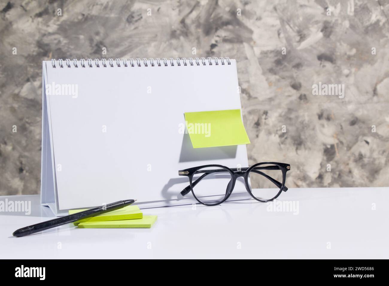 modello di calendario da scrivania vuoto, carta da lettere verde, penna, occhiali, tema business adatto per il mockup utente, astact grigio studio Foto Stock