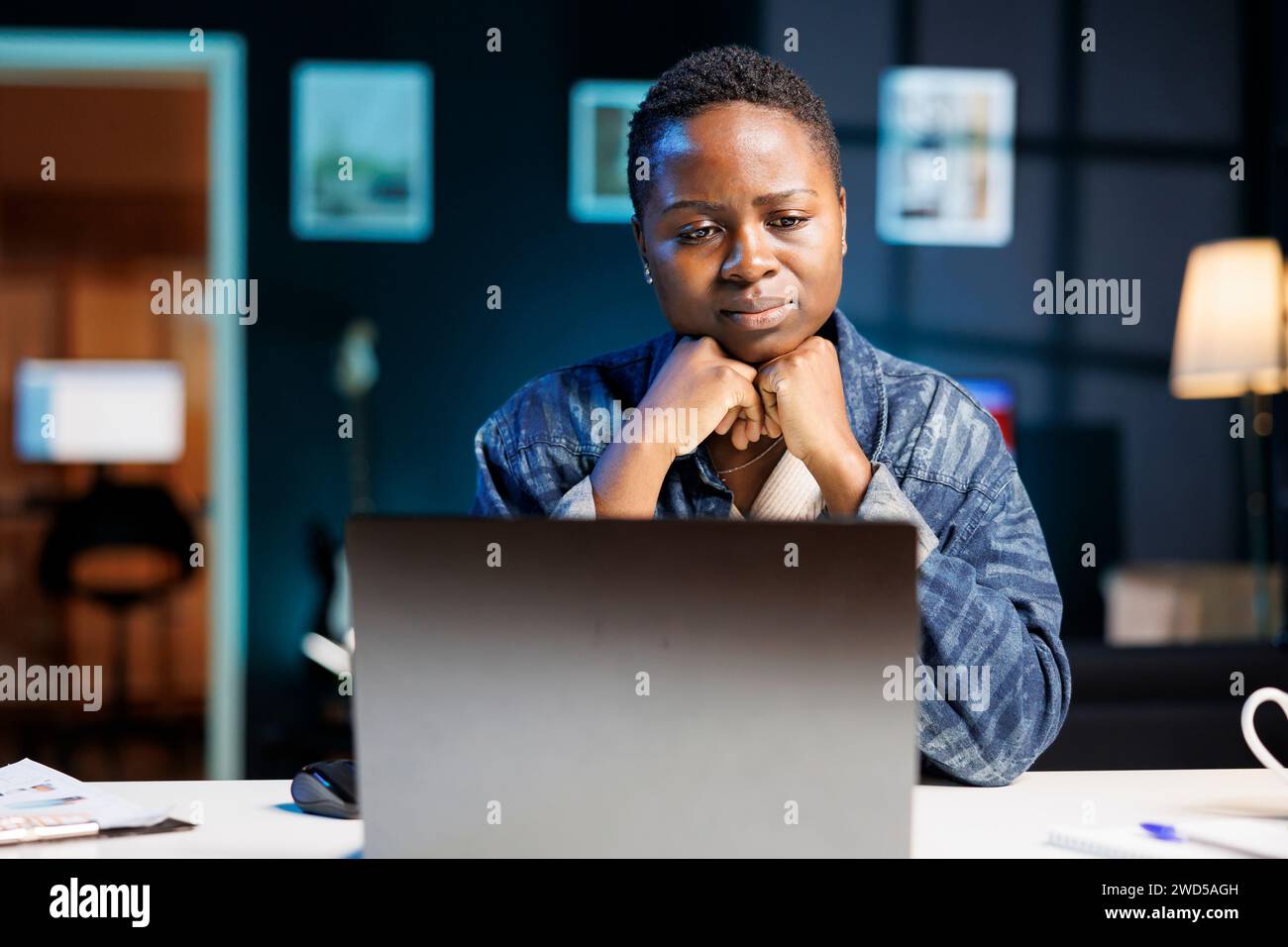 Una donna nera che si sente sconvolta e stanca sta guardando il suo personal computer sul tavolo. Studentessa universitaria afroamericana premurosa che utilizza un computer portatile digitale per leggere i giornali online. Foto Stock
