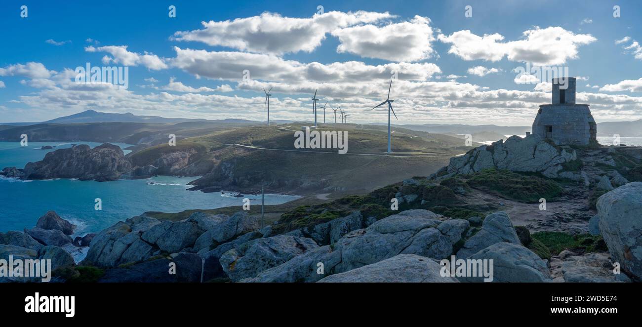 Un'antica torre in pietra sorge su un affioramento roccioso, una silenziosa testimonianza del passato in mezzo alla modernità delle turbine eoliche che coronano le dolci colline. Questo Foto Stock