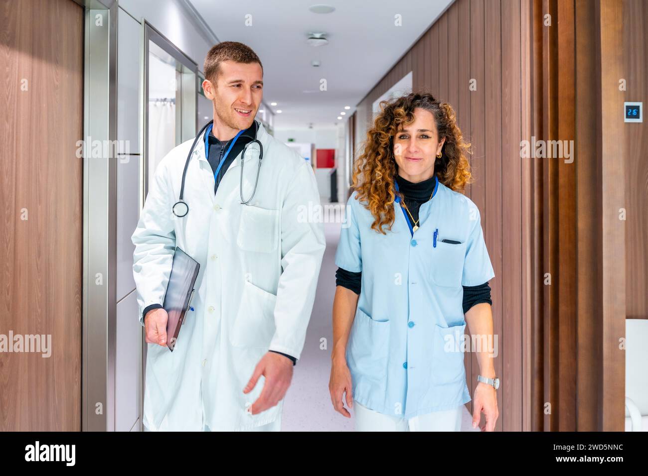 Operatori sanitari sorridenti e rilassati che camminano lungo un corridoio di un ospedale Foto Stock