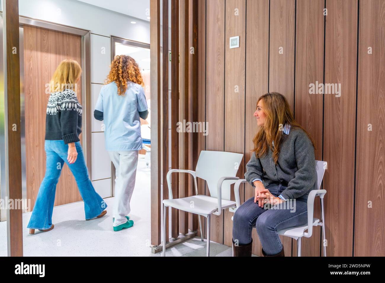 Infermiera che portava un paziente dalla sala d'attesa perché era il loro tempo di visita Foto Stock