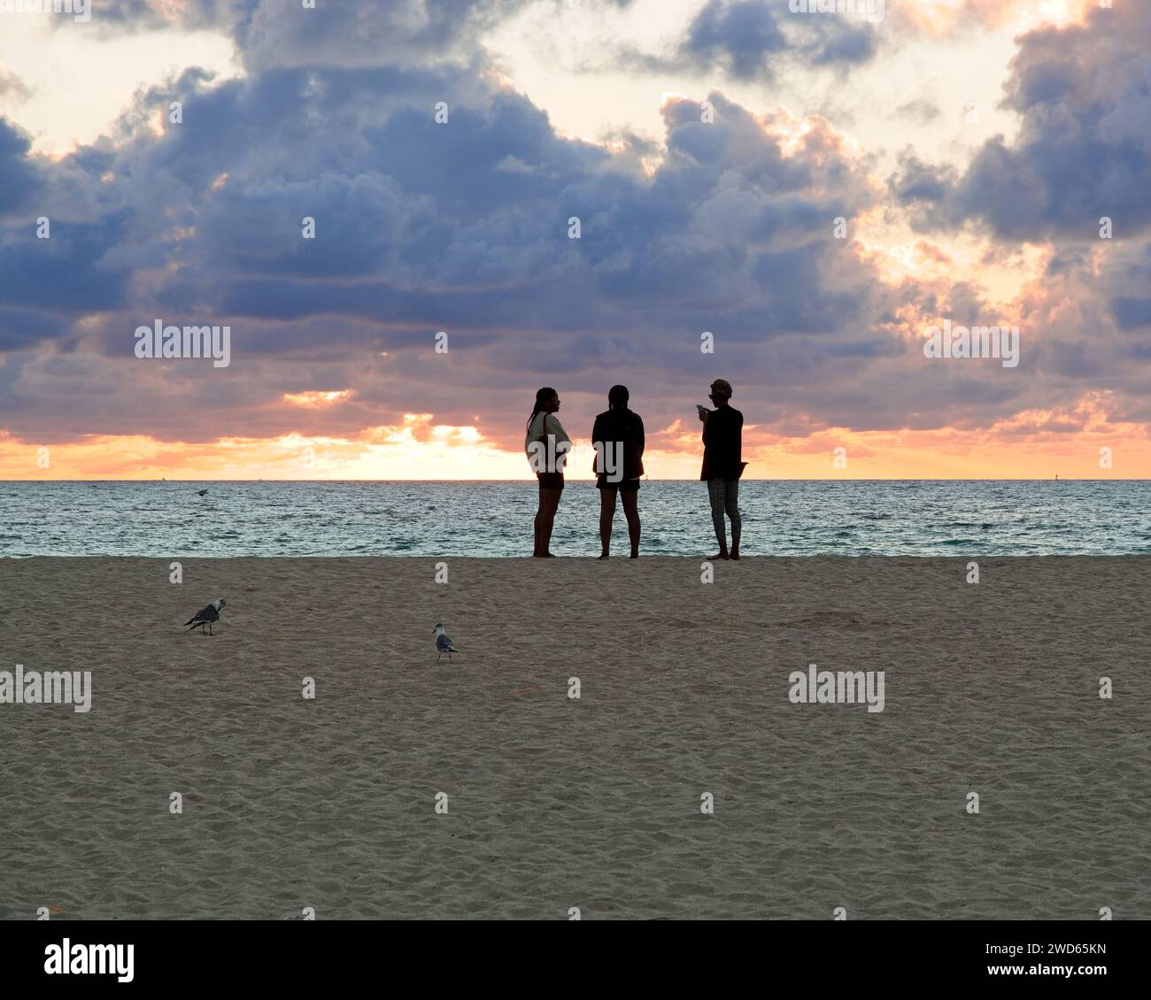La silhouette dei primi alpinisti saluta la prima luce dell'alba sull'orizzonte orientale di South Beach a Miami Beach Foto Stock