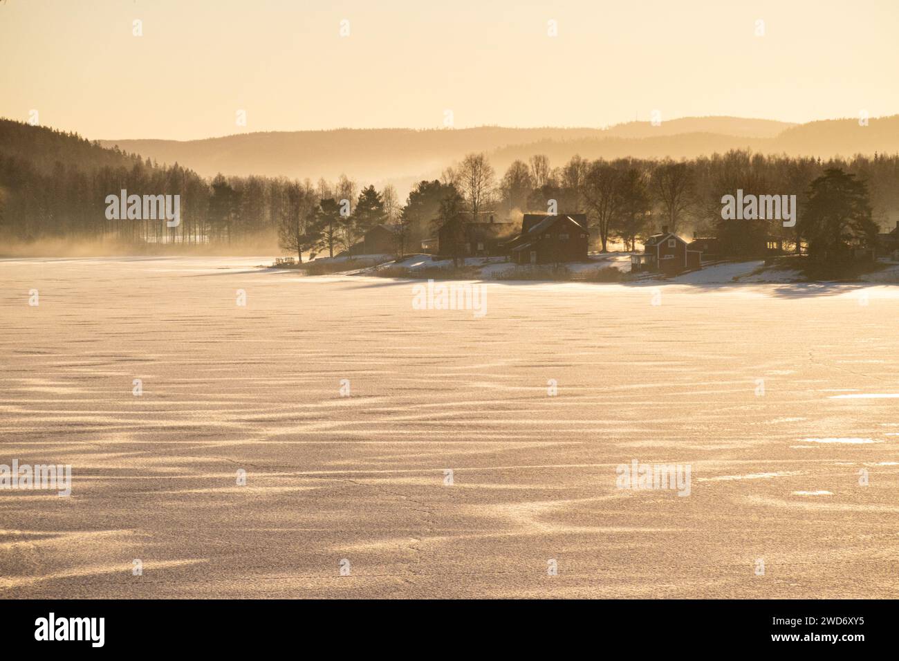 Le case costeggiano la riva di un lago ghiacciato a Grasmark, Svezia Foto Stock