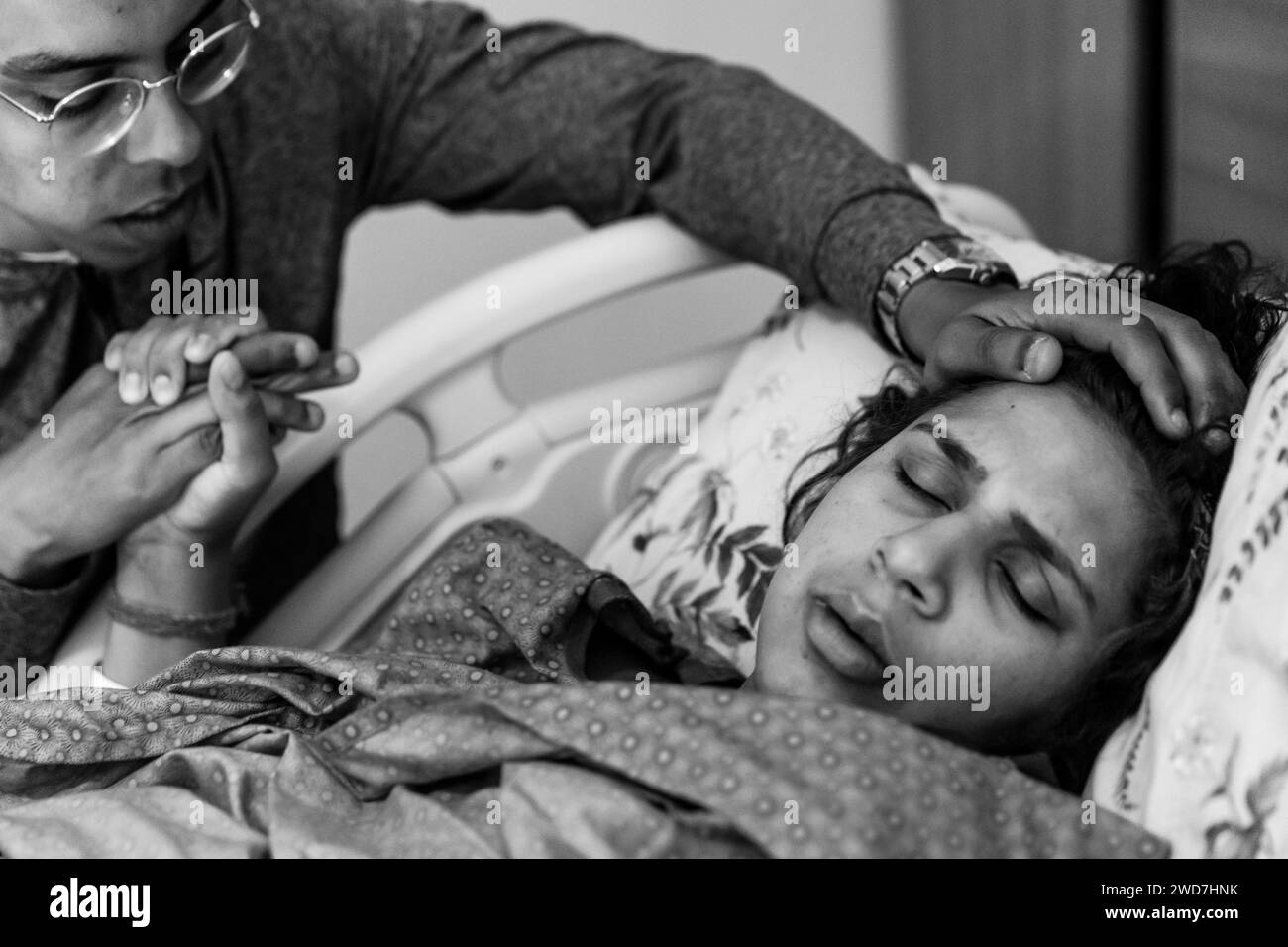 La madre esausta chiude gli occhi durante il travaglio mentre il marito la calma Foto Stock
