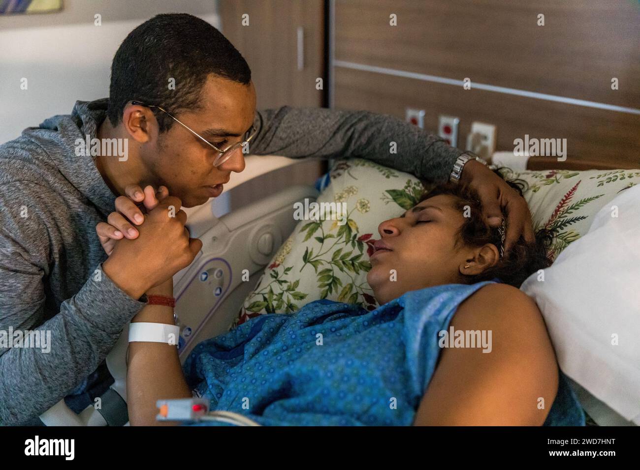 Papà conforta la mamma durante il travaglio in ospedale mentre si tiene la mano Foto Stock