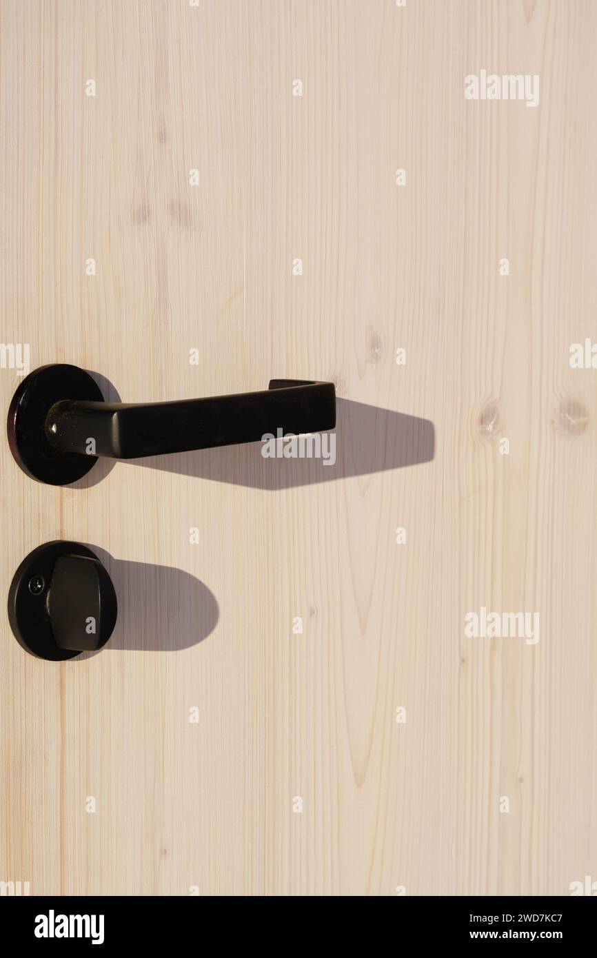 Maniglie delle portiere in legno e nere su una porta nera Foto Stock