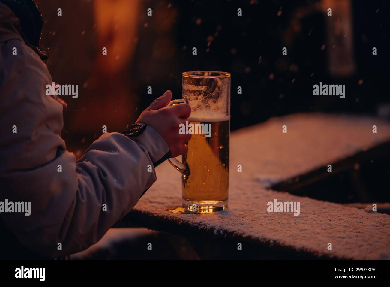 Persona che gusta la birra in un mercatino invernale di natale che nevica Foto Stock