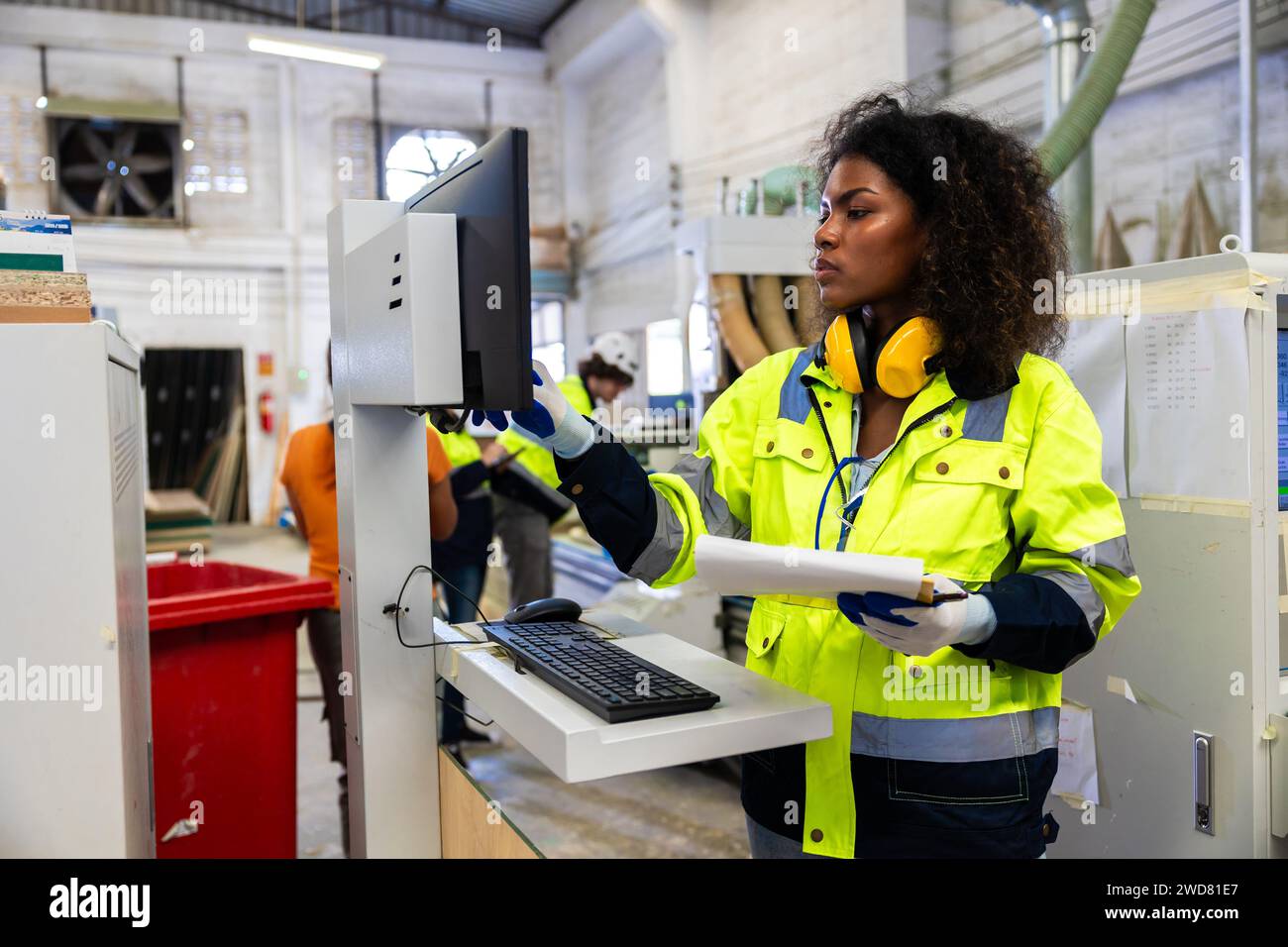 Le lavoratrici nere africane lavorano con l'industria della fabbrica di mobili della taglierina del legno con tuta di sicurezza Foto Stock