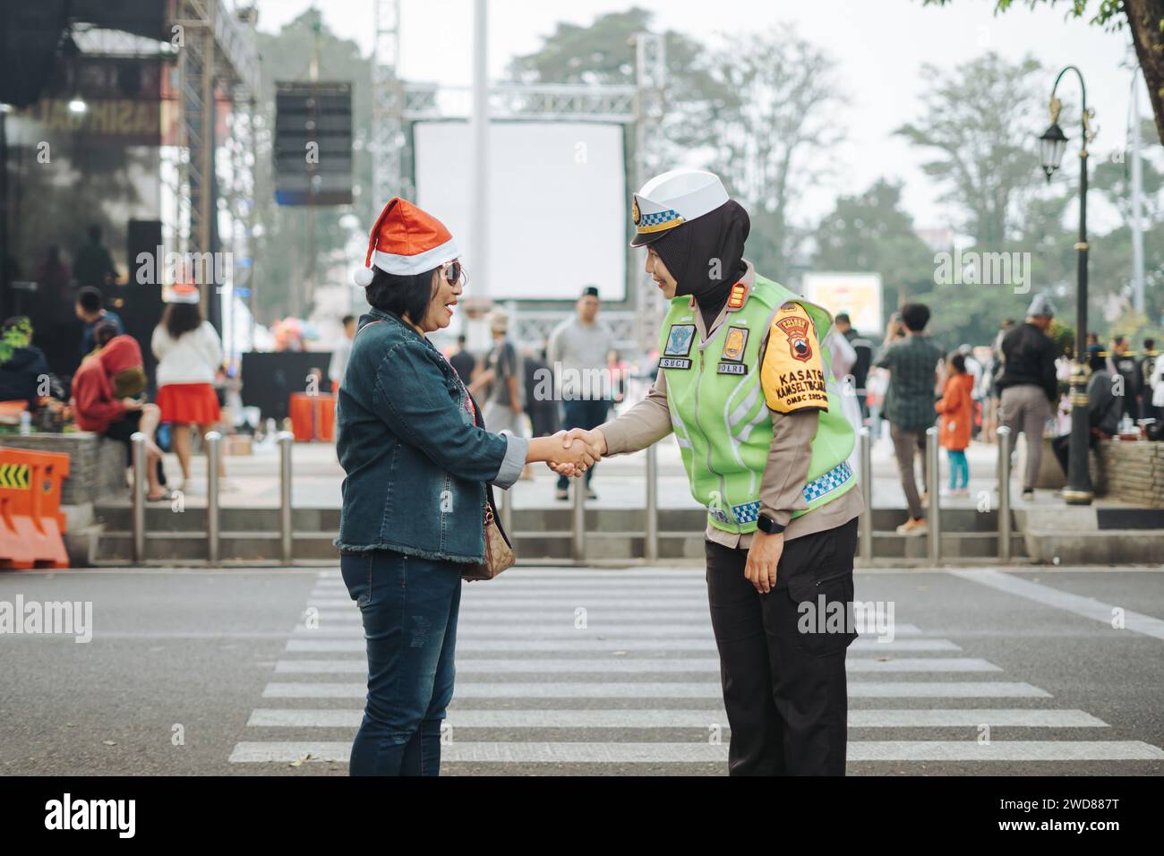 Donna della polizia (Polwan) che stringe la mano con cristiani o cattolici durante le celebrazioni natalizie a Salatiga, Indonesia - 25 dicembre 2023. Foto Stock