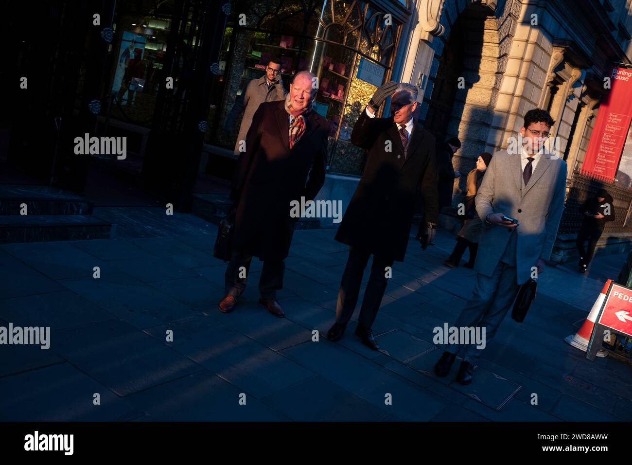 I pendolari si dirigono lungo Piccadilly in una serata d'inverno piena di sole mentre il sole basso tramonta a ovest verso Hyde Park, nel centro di Londra, nel Regno Unito Foto Stock