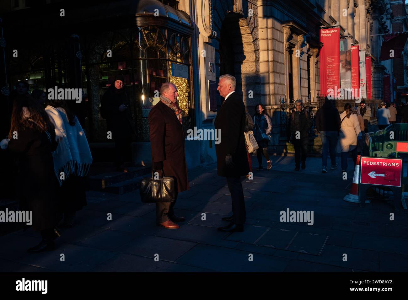 I pendolari si dirigono lungo Piccadilly in una serata d'inverno piena di sole mentre il sole basso tramonta a ovest verso Hyde Park, nel centro di Londra, nel Regno Unito Foto Stock