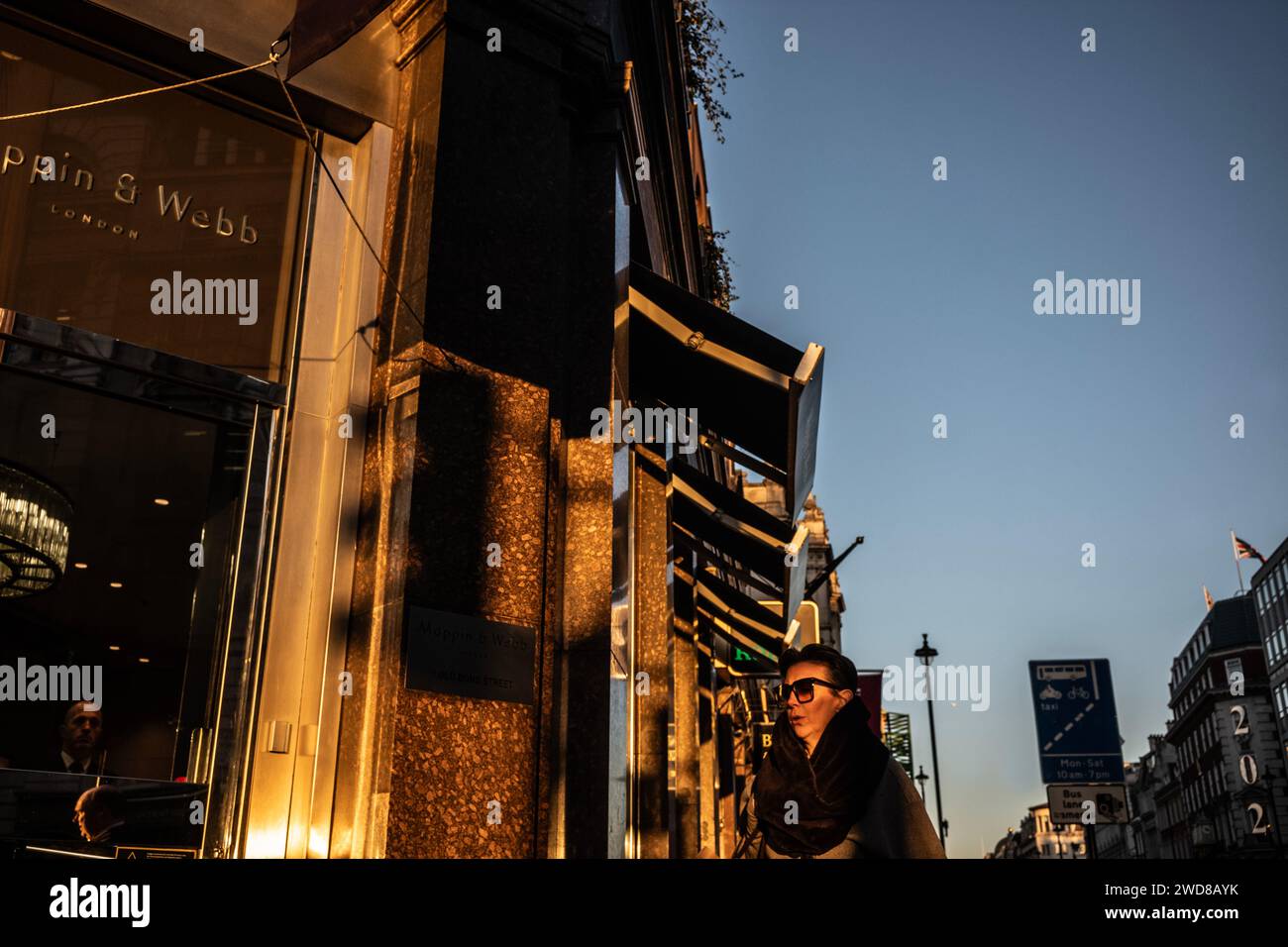 I pendolari si dirigono lungo Piccadilly in una serata d'inverno piena di sole mentre il sole basso tramonta a ovest verso Hyde Park, nel centro di Londra, nel Regno Unito Foto Stock