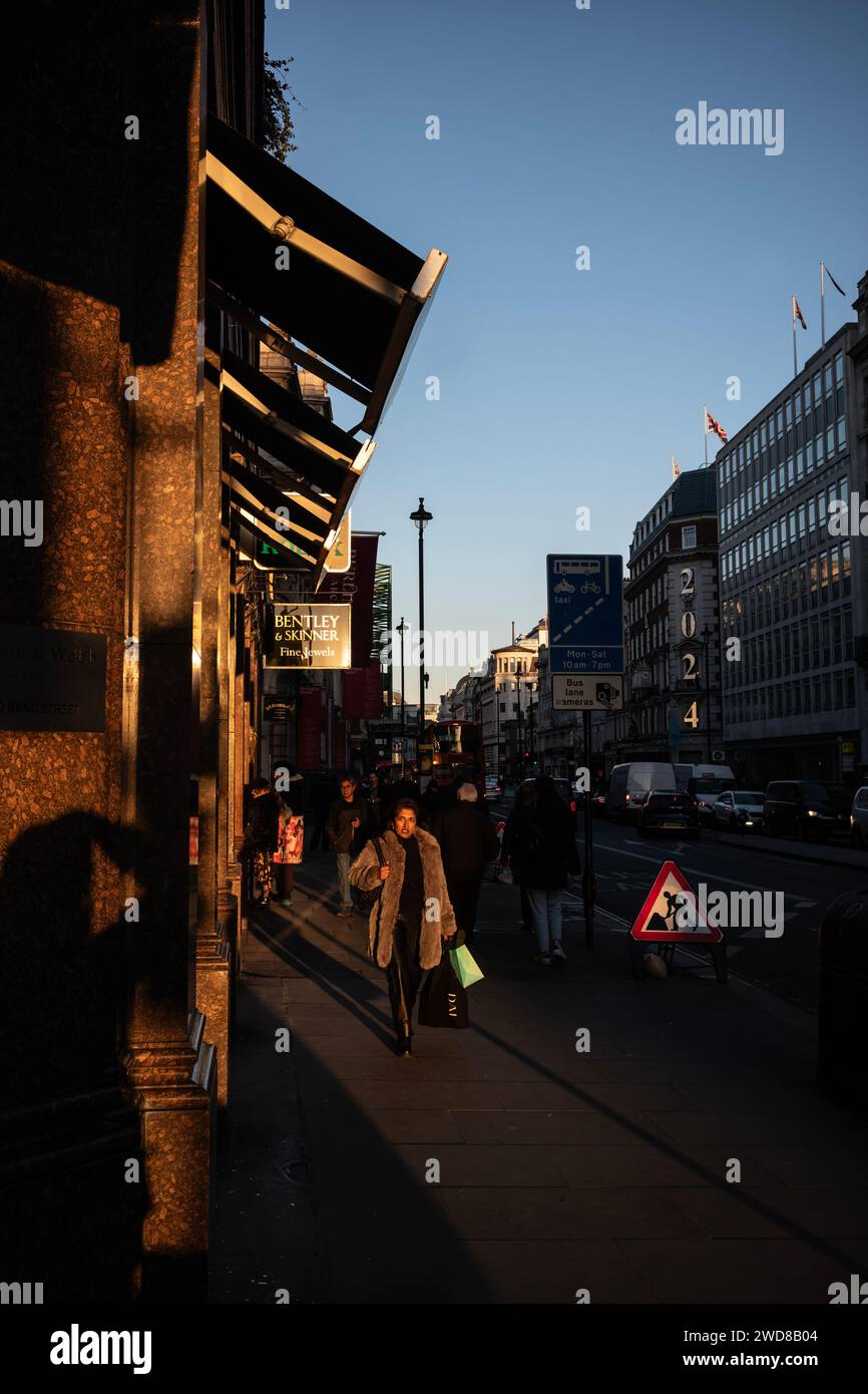 I pendolari si dirigono lungo Piccadilly in una serata d'inverno piena di sole mentre il sole basso tramonta a ovest verso Hyde Park, nel centro di Londra, nel Regno Unito Foto Stock
