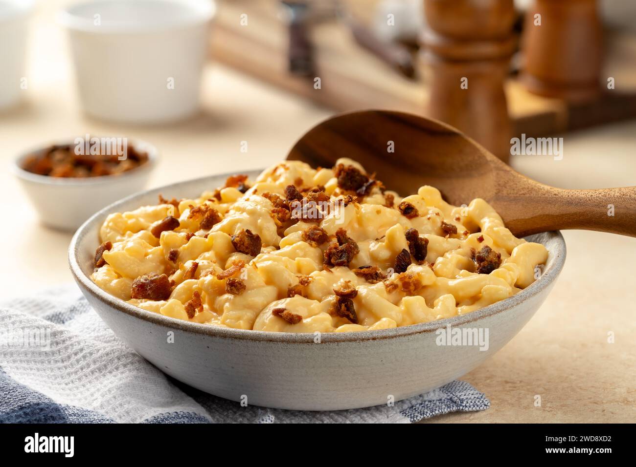 Maccheroni e formaggio con pancetta in una ciotola bianca e cucchiaio di legno Foto Stock