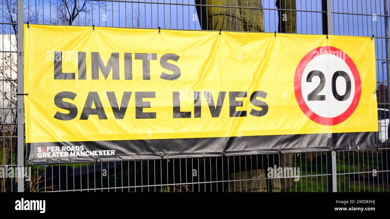 Il banner del limite di velocità dice "Limits Save Lives" con un suggerimento di 20 miglia all'ora sulla recinzione di una scuola elementare di Manchester, Regno Unito Foto Stock