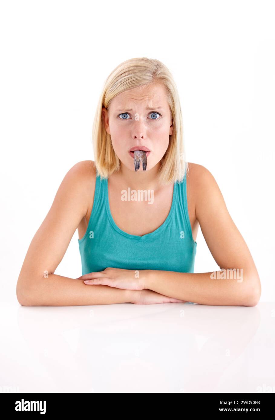 Confusa, donna e ritratto di mangiare pesce, coda o cibo strano in bocca su sfondo bianco dello studio. Pazzo, dieta e persona con strani frutti di mare Foto Stock