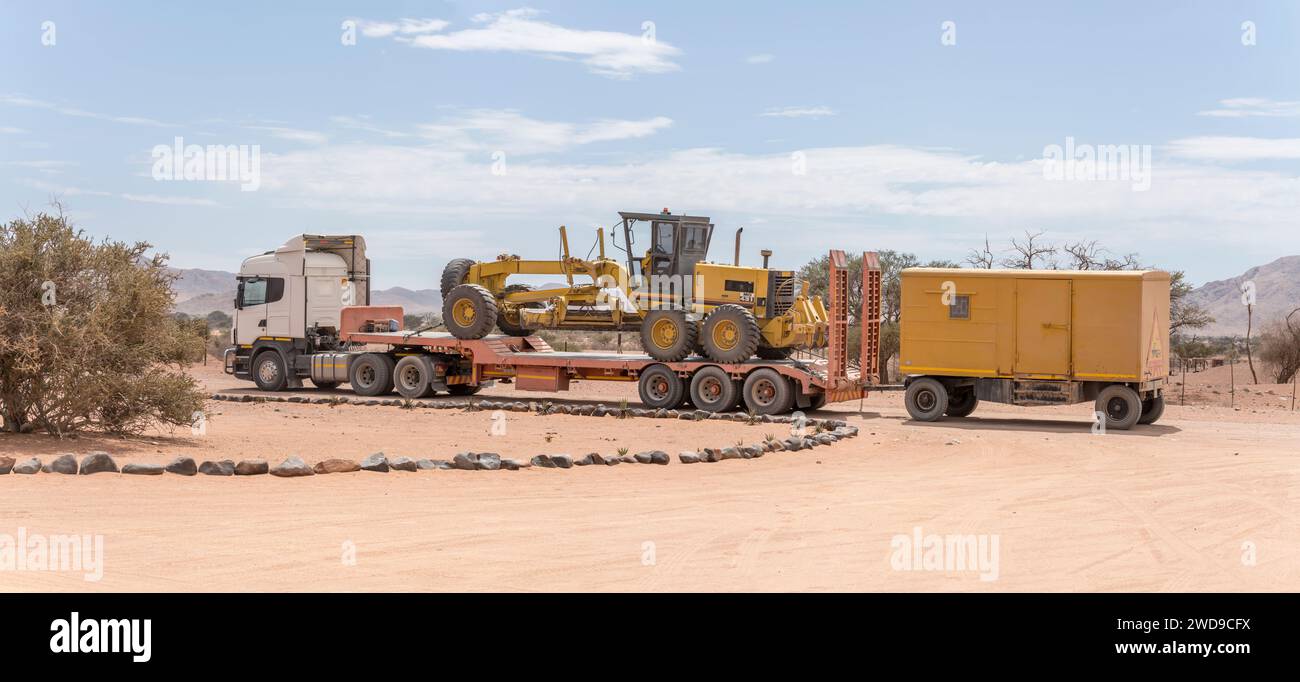 Attrezzature per la manutenzione di strade in ghiaia parcheggiate nel piccolo avamposto nel deserto di Naukluft, sparate con una brillante luce di tarda primavera a Betta, Namibia, Africa Foto Stock