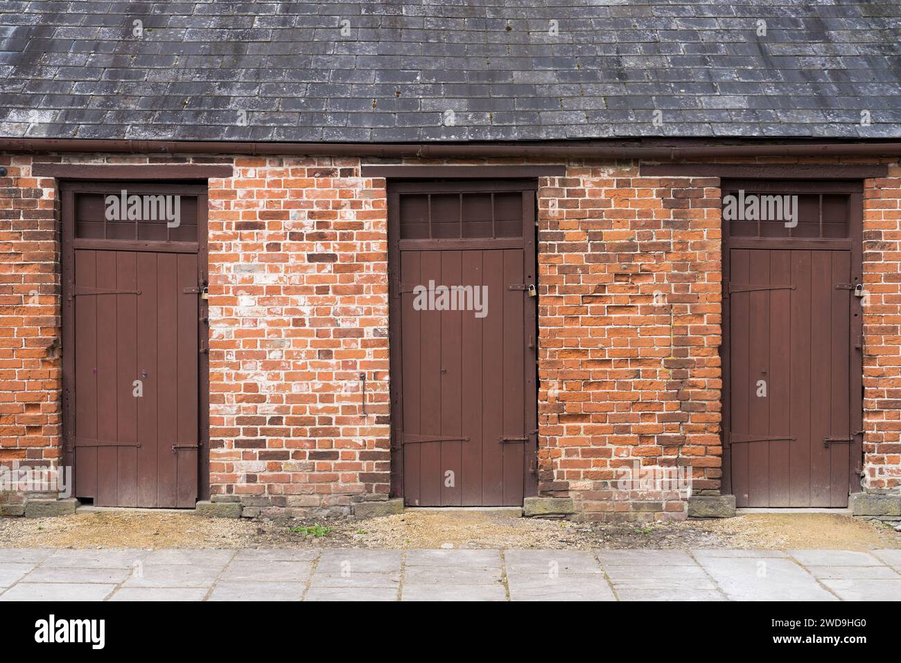 Edificio in mattoni con tre porte dipinte di marrone a Tredegar House, Newport, Galles, Regno Unito Foto Stock