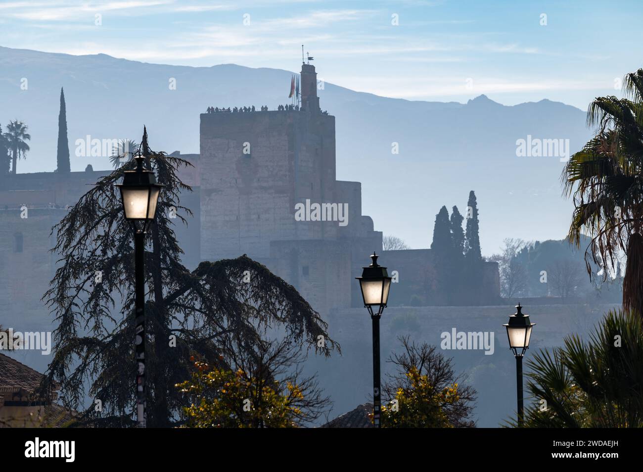 Vista della Torre de la Vela dell'Alhambra (Granada, Spagna) all'alba, con tre lampioni in primo piano Foto Stock