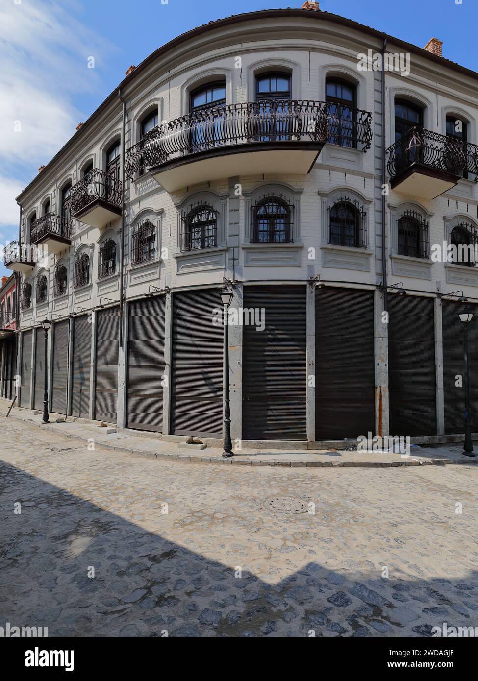 257 Casa ad angolo in stile neoclassico bianco-grigio presso l'angolo acciottolato di Rrugica Alush Koprencka e Rrugica Petraq Nasi, area del vecchio Bazaar. Korca-Albania. Foto Stock