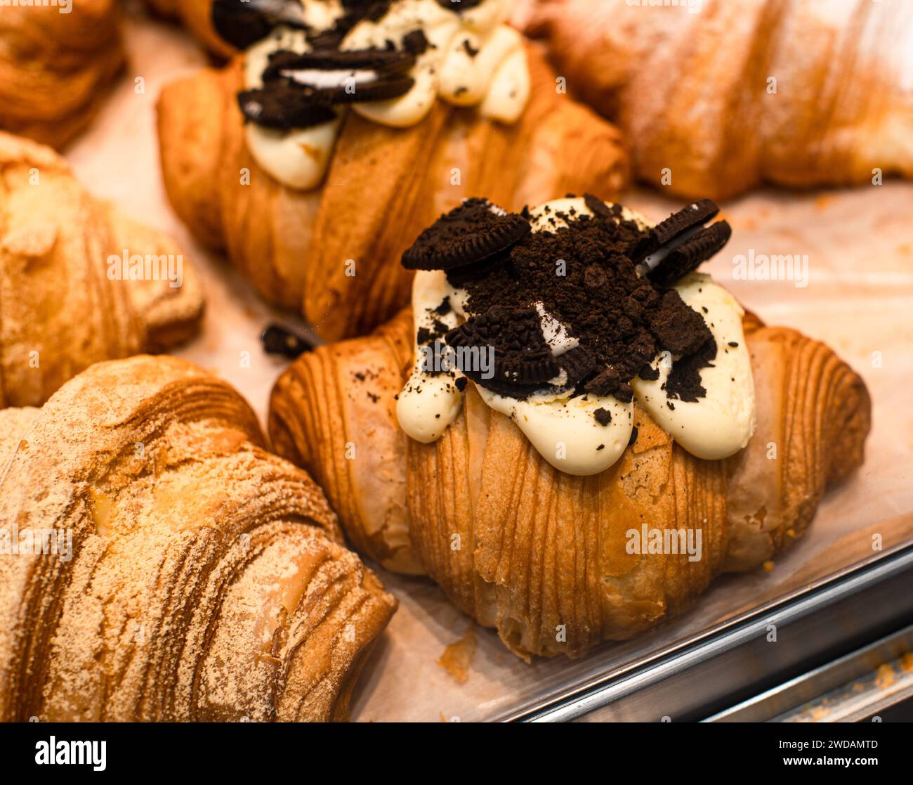 Il delizioso pane posto su ripiani in legno ha forme squisite e viene illuminato da luci calde. Foto Stock