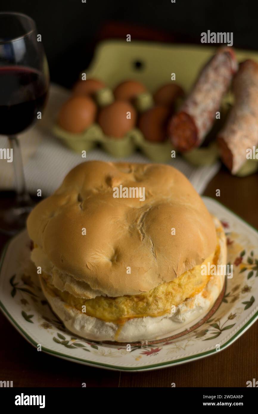 Panino con omelette di patate con pane artigianale rotondo e bicchiere di vino in verticale Foto Stock