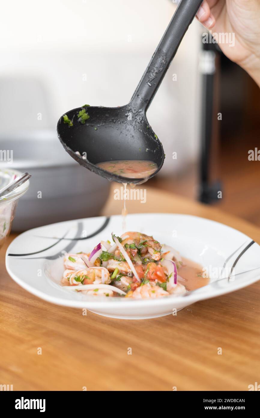 appetitoso ceviche di gamberi con cipolle, pomodoro e spezie come ingredienti, foto studio per il menu del ristorante, zuppa sana con pesce, dettagli del piatto Foto Stock