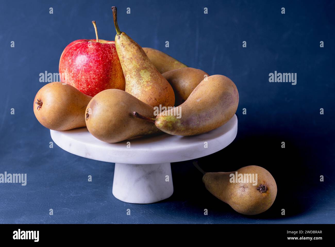 Pere e frutti di mela su un supporto per torta con pietra bianca. Frutta. Foto Stock