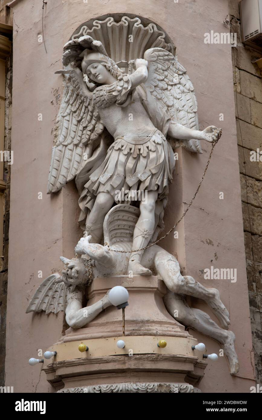 San Michele Arcangelo uccide il diavolo che si trova ai suoi piedi. Fregio di statue sugli edifici. La Valletta, Malta 2024 2020 HOMER SYKES Foto Stock