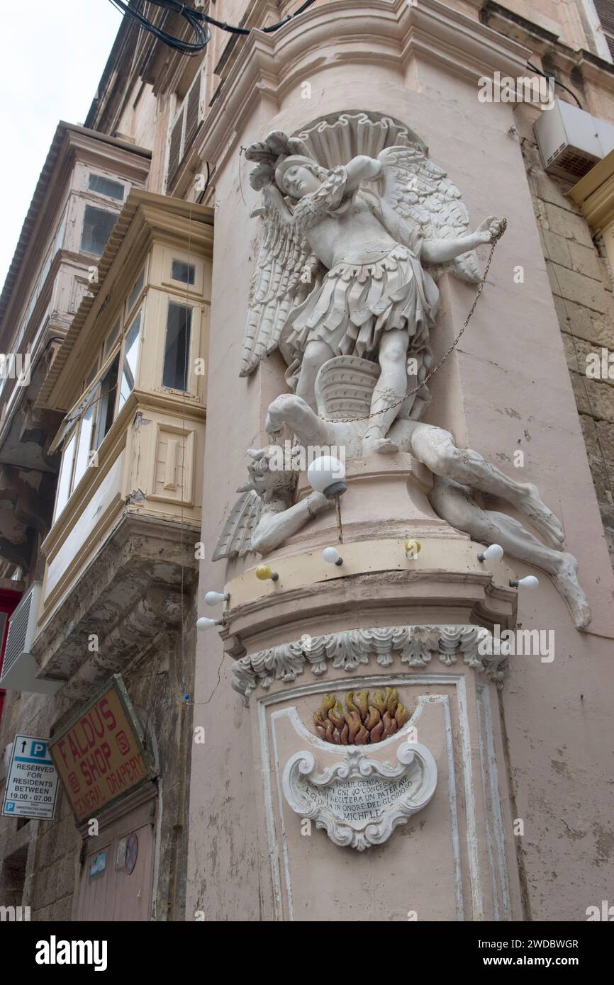San Michele Arcangelo uccide il diavolo che si trova ai suoi piedi. Statua fregio su edifici con balconi coperti a la Valletta, Malta, HOMER SYKES anni '2024 2020 Foto Stock