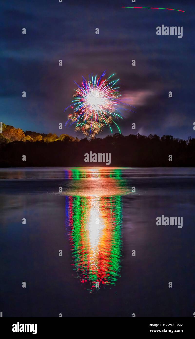 Brillanti fuochi d'artificio che si riflettono nelle acque fisse del lago Macquarie in Australia ai fuochi d'artificio di Capodanno a Swansea. Foto Stock