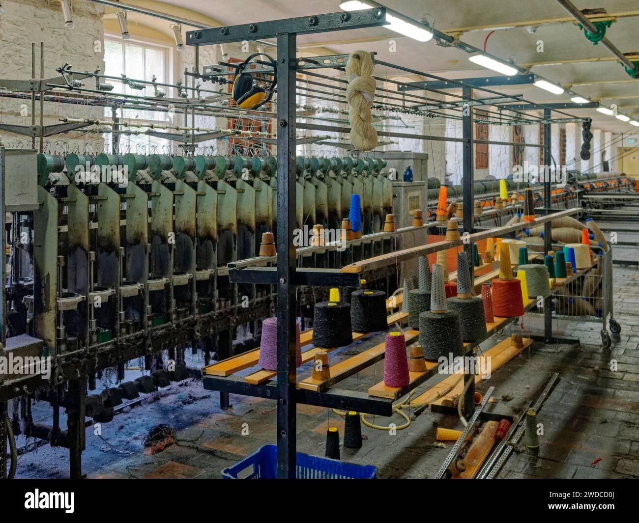 Vista interna di una fabbrica tessile con macchine e bobine colorate di filato. New Lanark, sito patrimonio dell'umanità dell'UNESCO. Scozia, Gran Bretagna Foto Stock