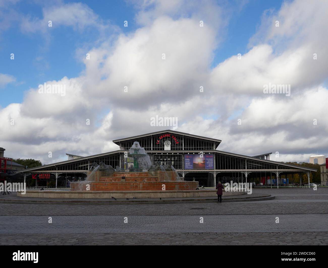 Un grande edificio con una fontana di fronte e gente che cammina attraverso una piazza, grande Halle de la Villette. Parigi Foto Stock