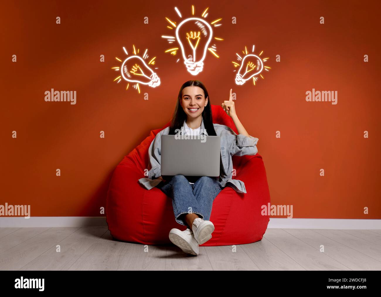 Generazione di idee. Donna con computer portatile in camera. Illustrazioni di una lampadina illuminante sopra di lei Foto Stock