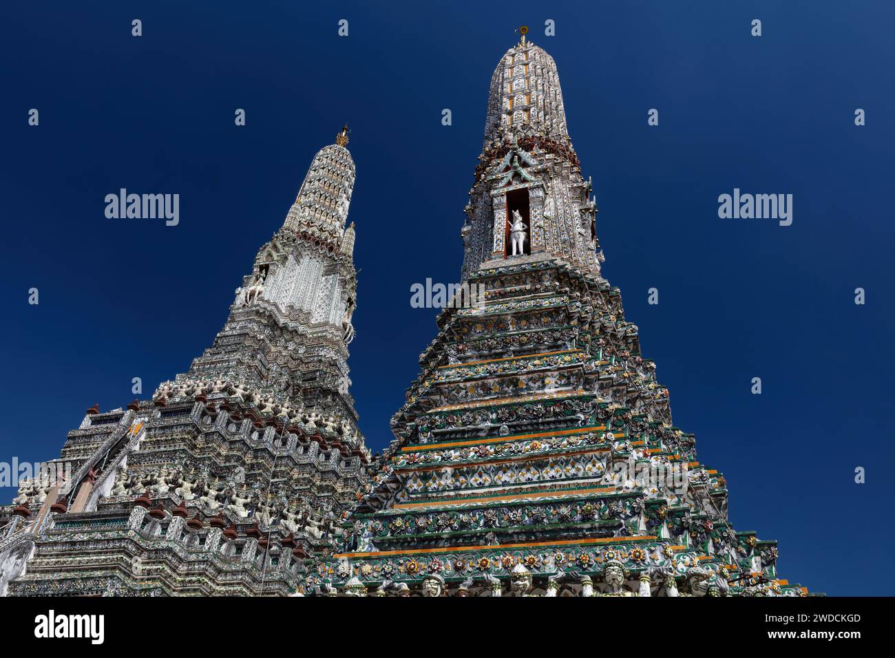 Due prangs al Wat Arun (Tempio dell'Alba) a Bangkok, Thailandia. Decorazioni intricate sulle strutture; dietro il cielo blu profondo. Foto Stock