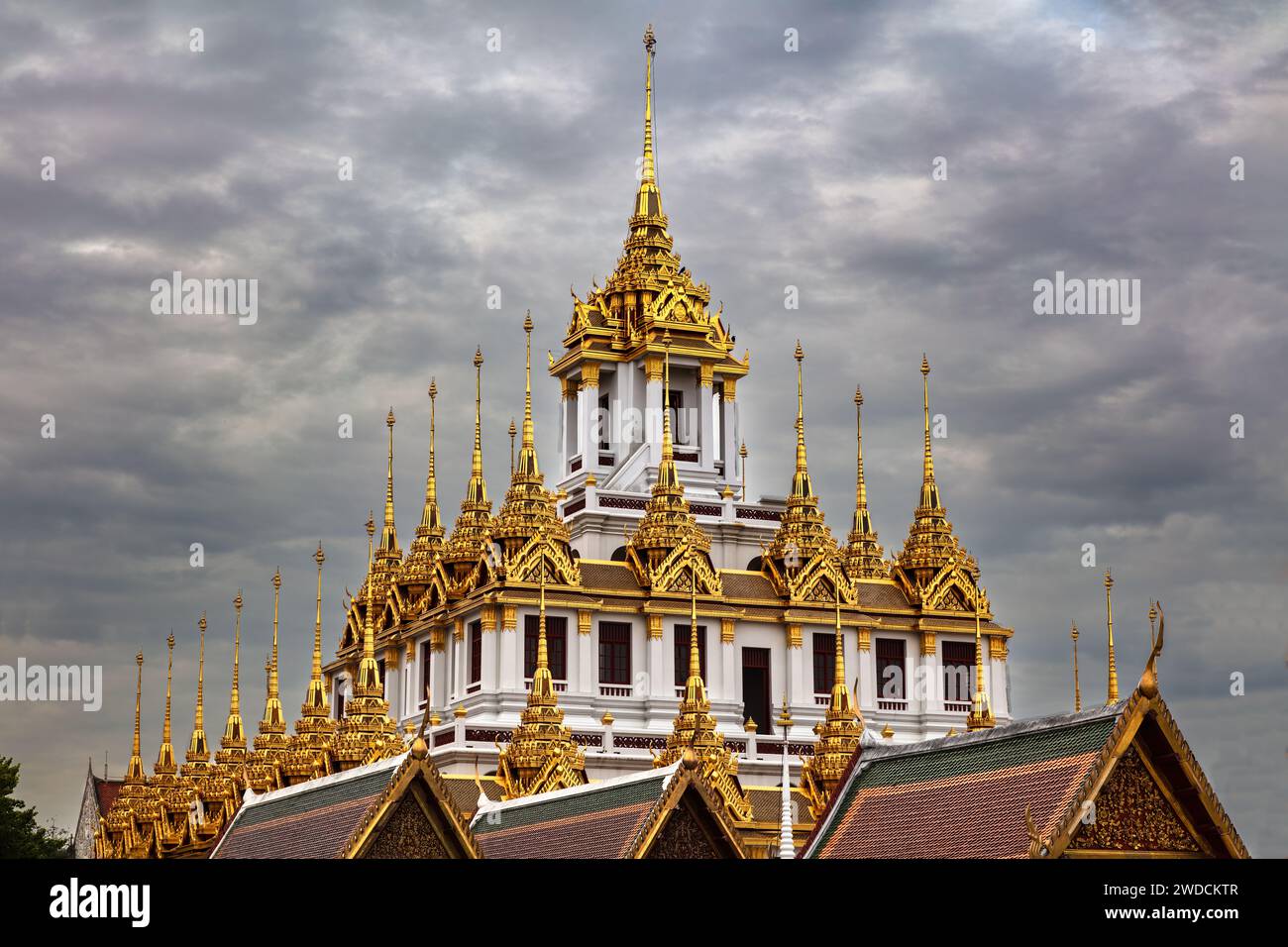 Tempio dei metalli (Wat Ratchanatdaram) a Bangkok, Thailandia. Guglie metalliche sul tetto. Cielo nuvoloso scuro sopra la testa Foto Stock