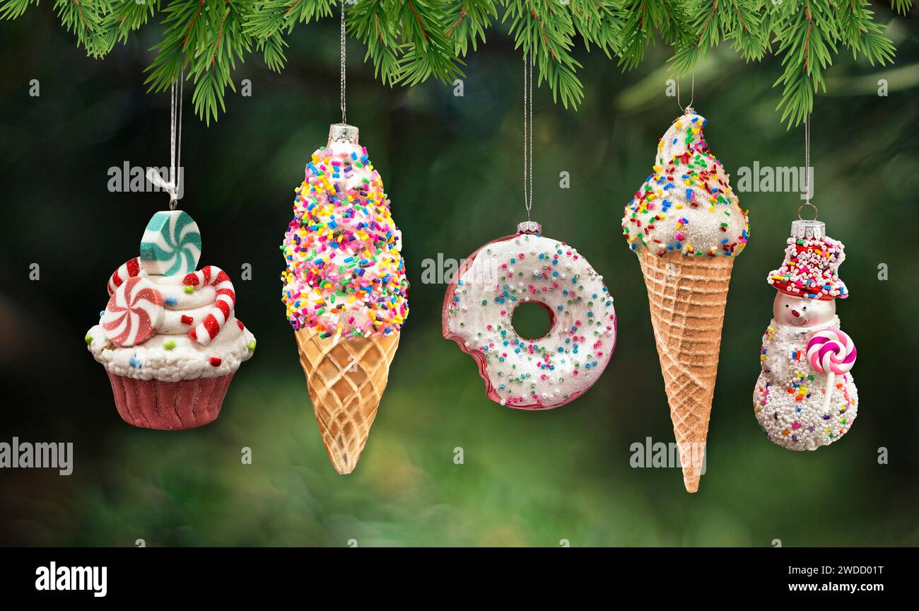Ornamenti di Natale dolci e dessert: Cupcake, cono gelato, ciambella, pupazzo di neve. Isolato su sfondo bianco bokeh con aghi di pino in cima. Foto Stock