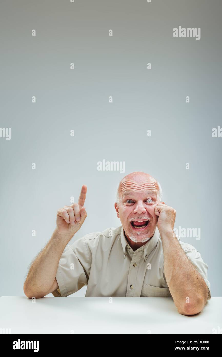L'uomo esuberante punta verso l'alto, l'espressione facciale trasmette un'improvvisa esplosione di ispirazione o intuizione Foto Stock