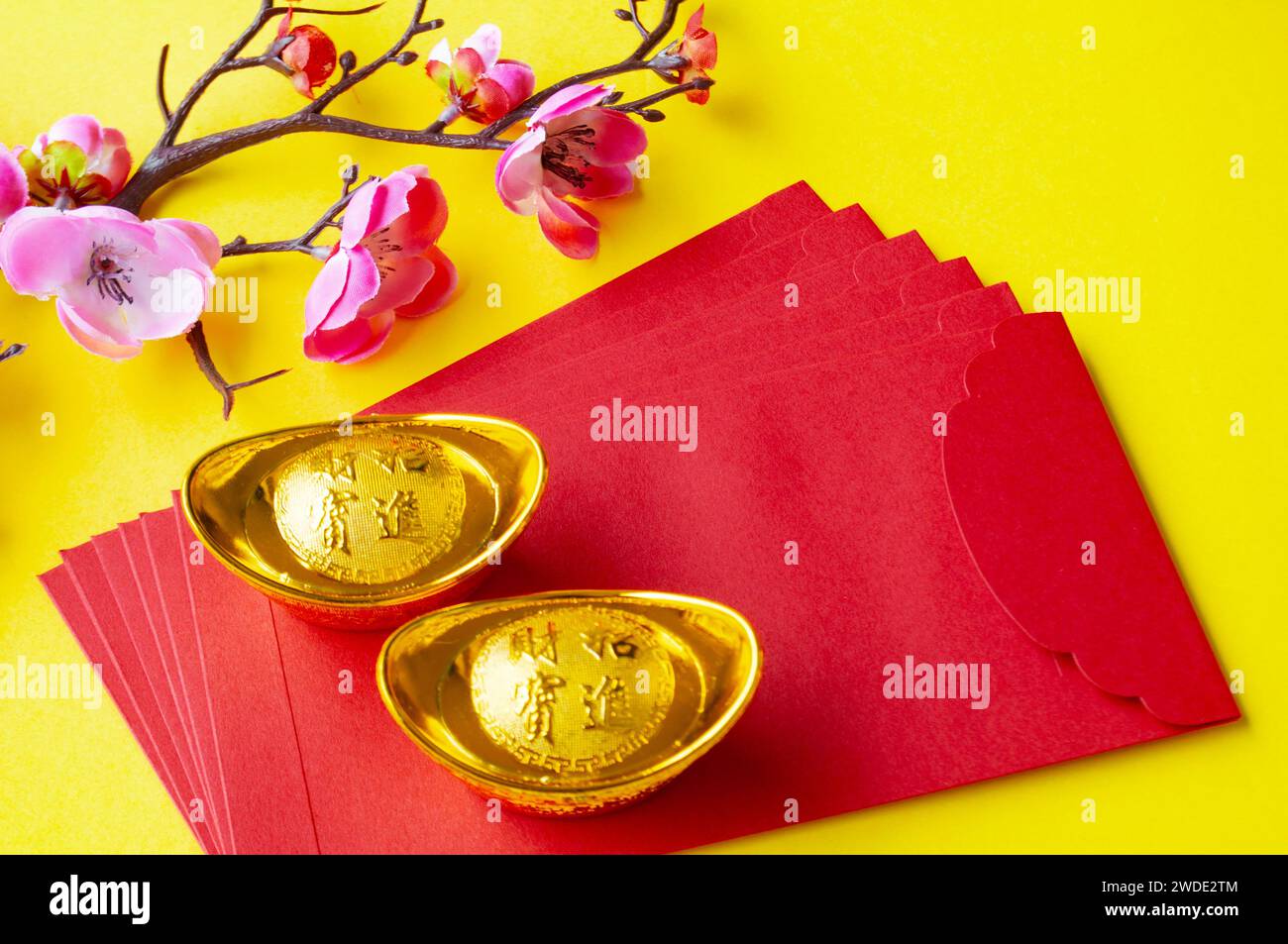 Vista dall'alto del pacchetto rosso del capodanno cinese, fiori di ciliegio e lingotti dorati. Foto Stock