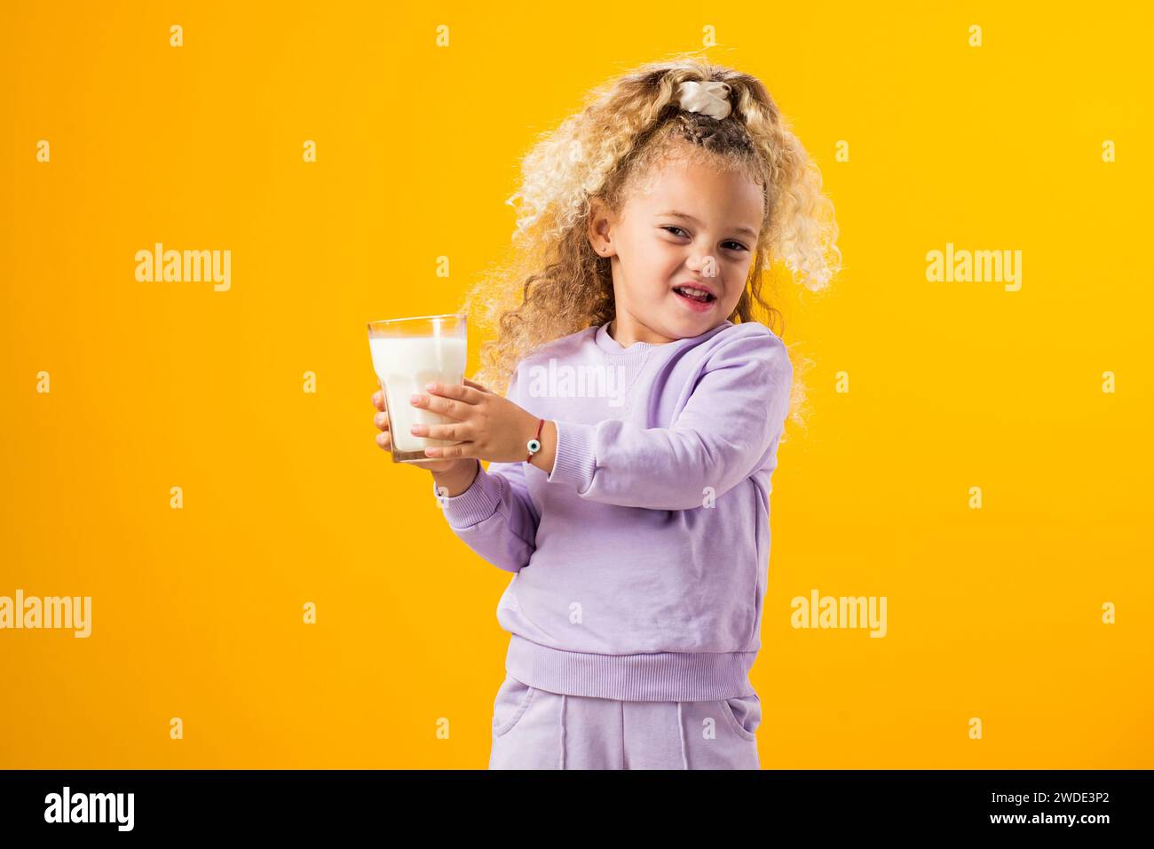 Fastidio da latte: Ragazza espressiva che regge un bicchiere di latte, che illustra l'intolleranza al lattosio e l'importanza dell'assistenza sanitaria. Espressione sgradevole r Foto Stock
