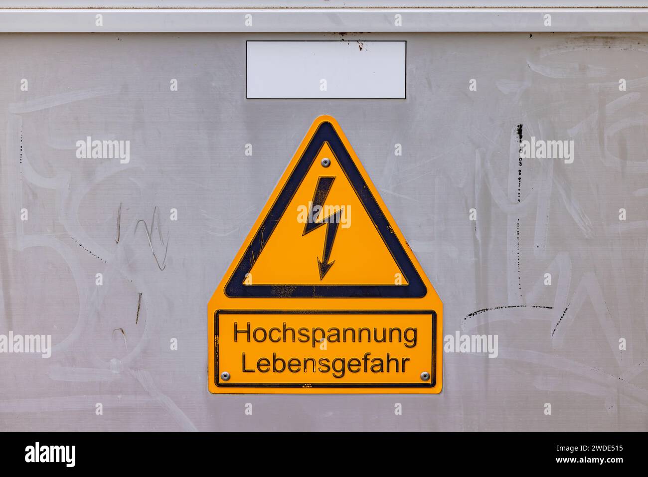 Segnale giallo di avvertimento alta tensione pericolo di morte sulla scatola elettrica con testo in tedesco Foto Stock