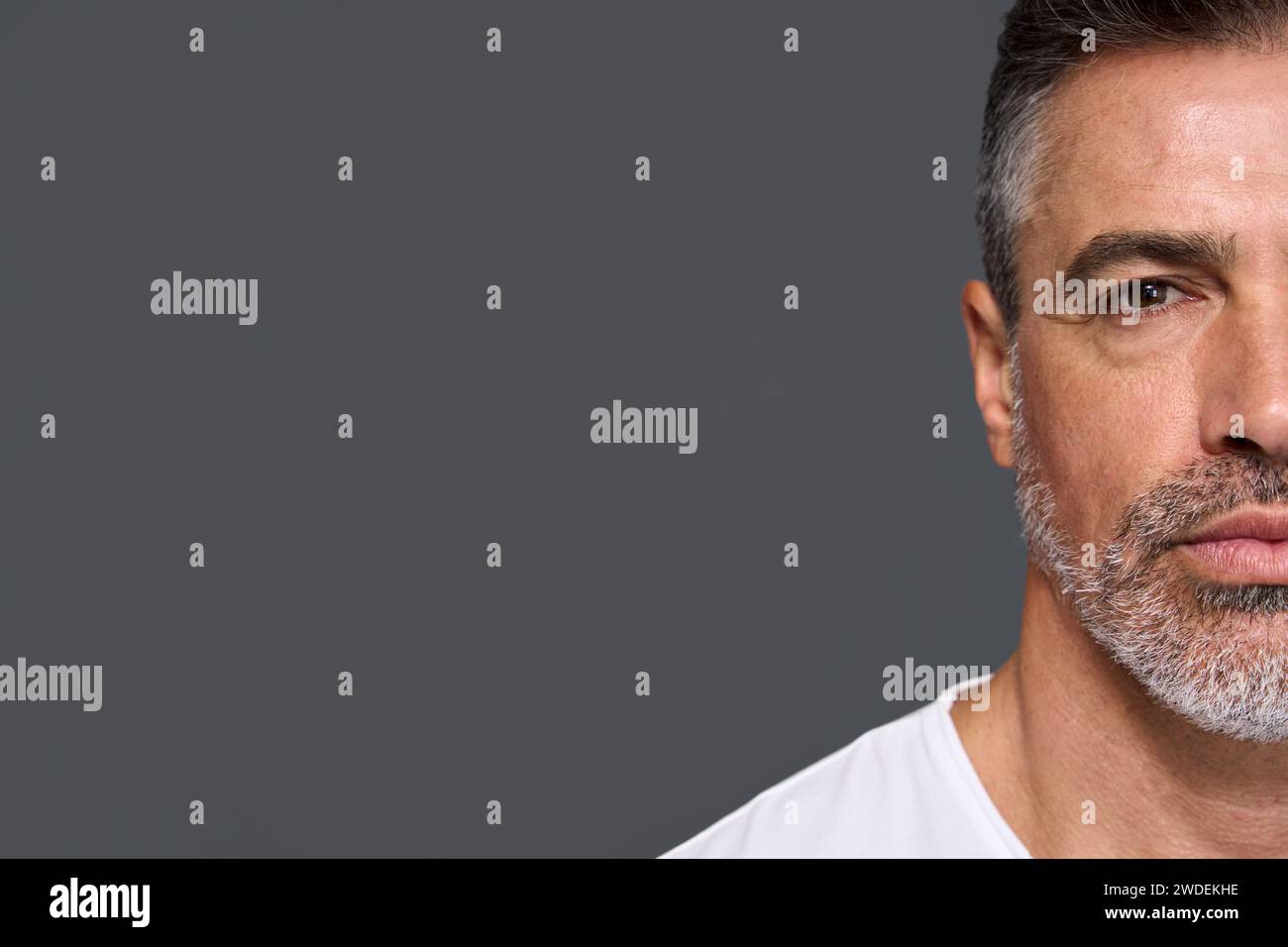 Un uomo anziano serio isolato su sfondo grigio. Primo piano in verticale. Foto Stock